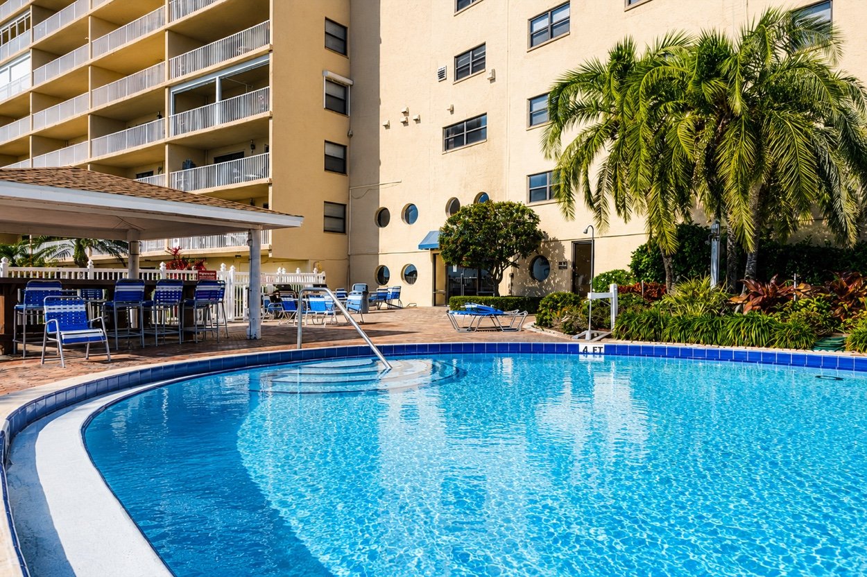 The pool curving away beneath the building, with palms and the poolside bar
