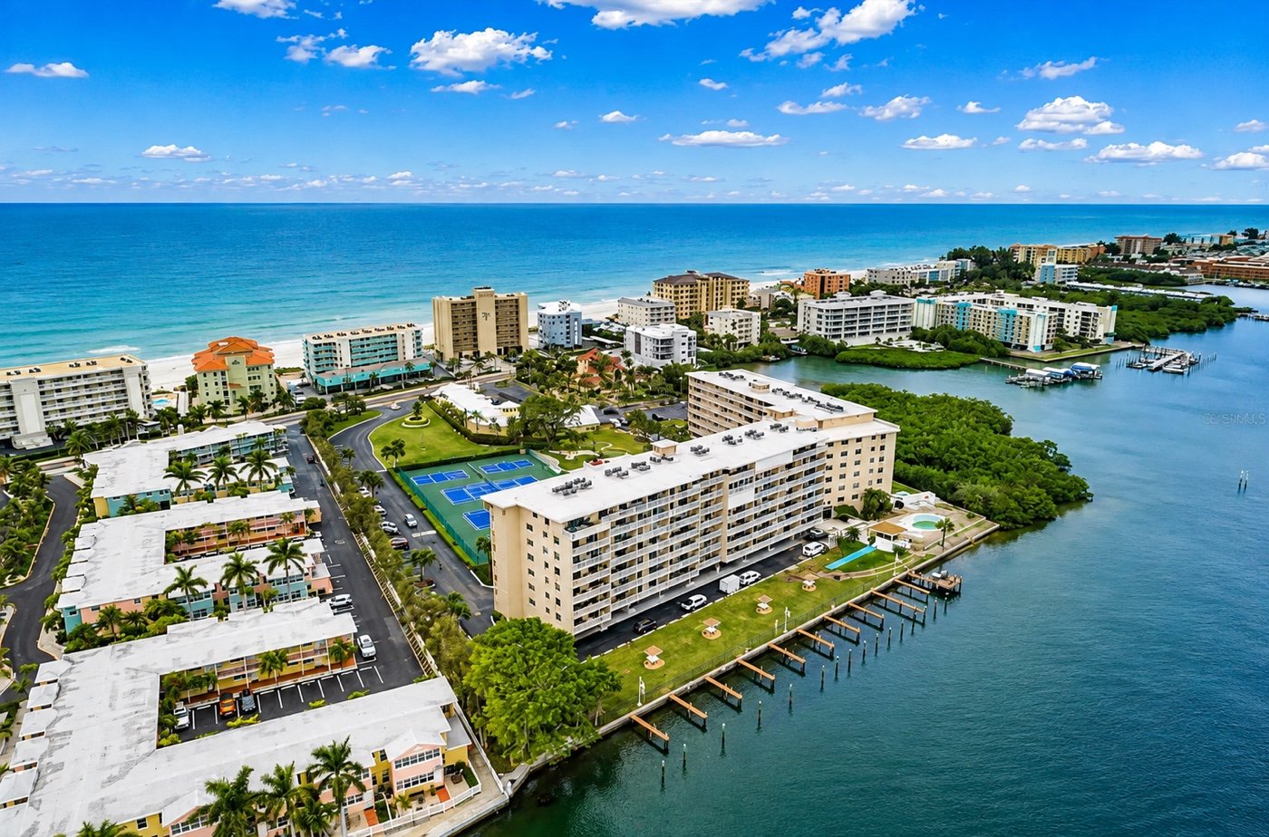 Wide aerial of Indian Shores: the Gulf beach running the length of the barrier island, with the Intracoastal and the marina on the bay side