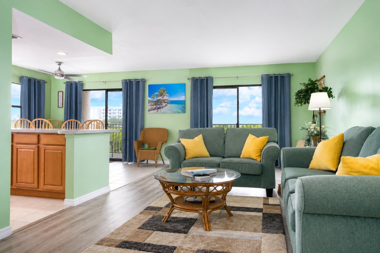 The living room, with two sofas, a rattan coffee table and windows toward the water